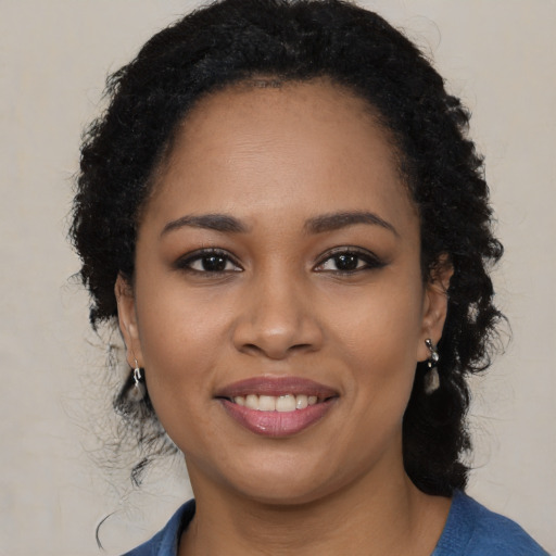 Joyful black young-adult female with long  black hair and brown eyes