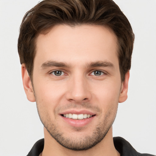 Joyful white young-adult male with short  brown hair and grey eyes