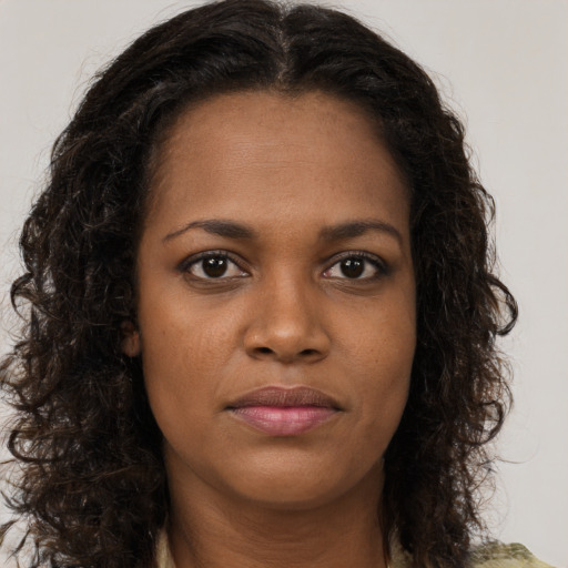 Joyful black young-adult female with long  brown hair and brown eyes