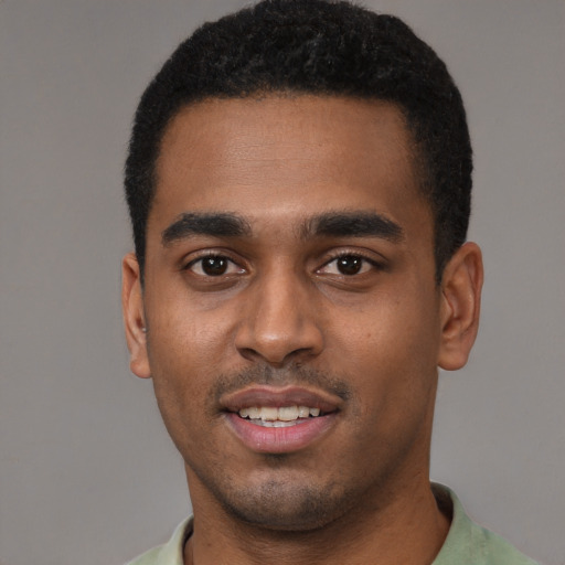 Joyful black young-adult male with short  black hair and brown eyes