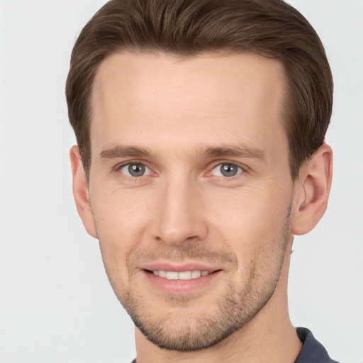 Joyful white young-adult male with short  brown hair and grey eyes