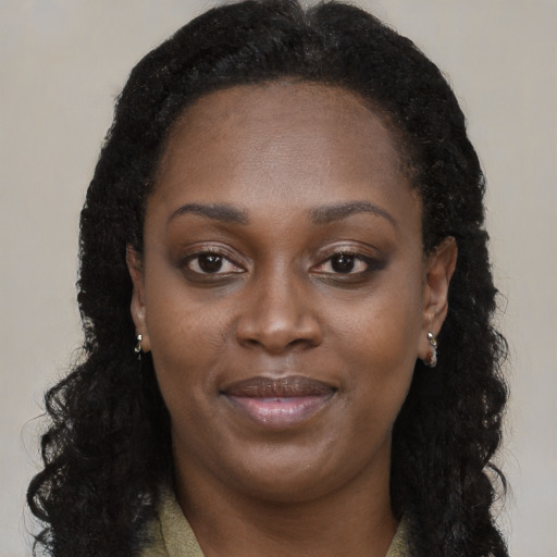 Joyful black young-adult female with long  brown hair and brown eyes