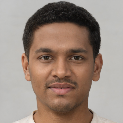 Joyful black young-adult male with short  black hair and brown eyes