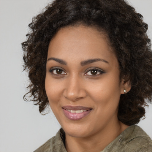 Joyful black young-adult female with long  brown hair and brown eyes