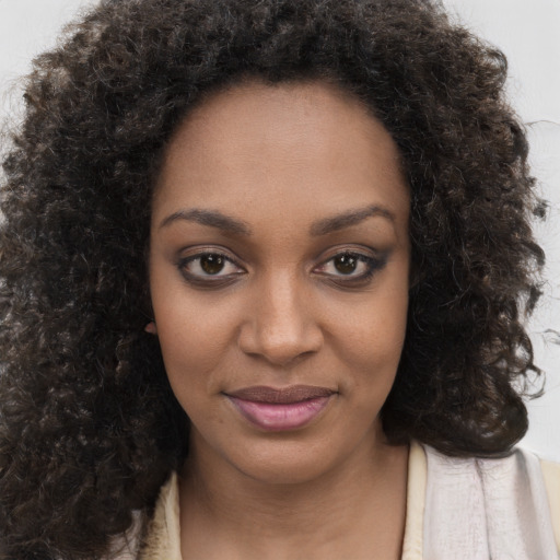 Joyful black young-adult female with long  brown hair and brown eyes