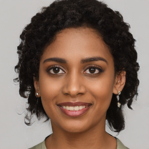 Joyful black young-adult female with long  black hair and brown eyes