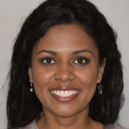 Joyful black young-adult female with long  brown hair and brown eyes