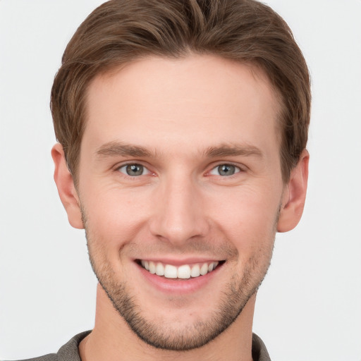 Joyful white young-adult male with short  brown hair and grey eyes