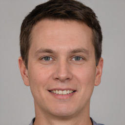 Joyful white young-adult male with short  brown hair and grey eyes