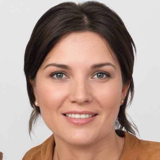 Joyful white young-adult female with medium  brown hair and grey eyes