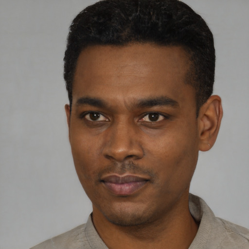 Joyful black young-adult male with short  black hair and brown eyes