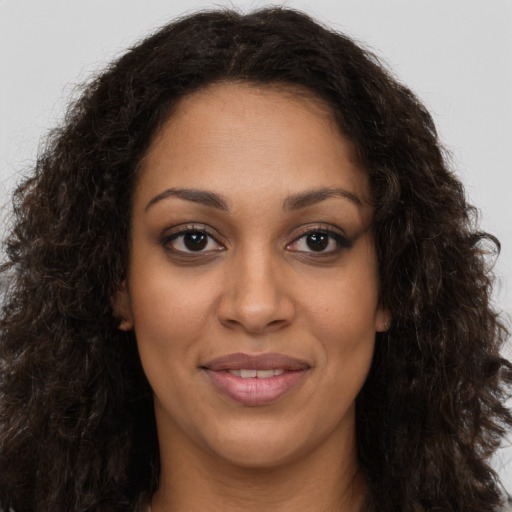 Joyful black young-adult female with long  brown hair and brown eyes