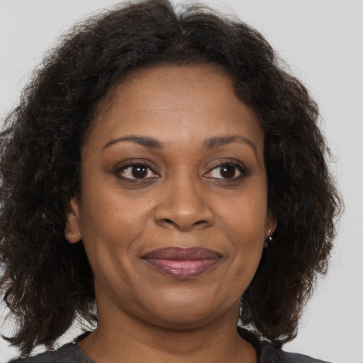 Joyful black adult female with long  brown hair and brown eyes