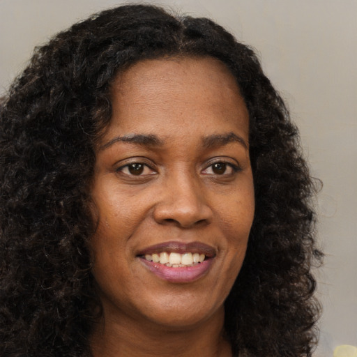 Joyful black young-adult female with long  brown hair and brown eyes