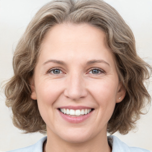 Joyful white young-adult female with medium  brown hair and blue eyes