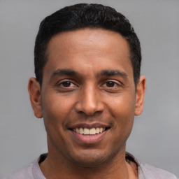 Joyful latino young-adult male with short  black hair and brown eyes
