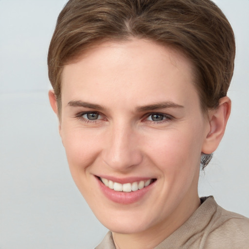 Joyful white young-adult female with short  brown hair and grey eyes