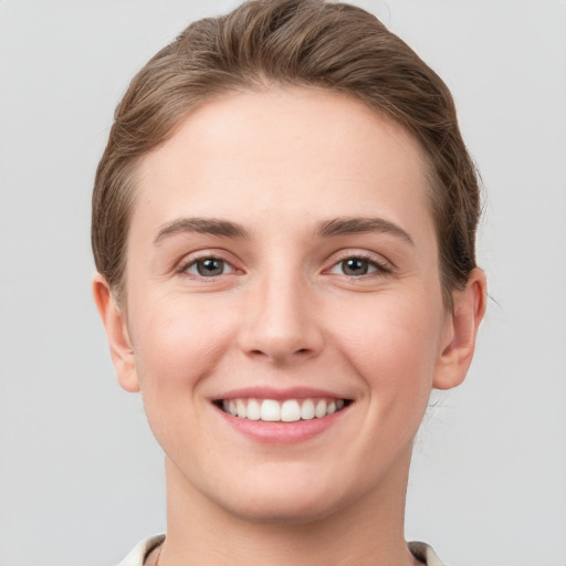 Joyful white young-adult female with short  brown hair and grey eyes