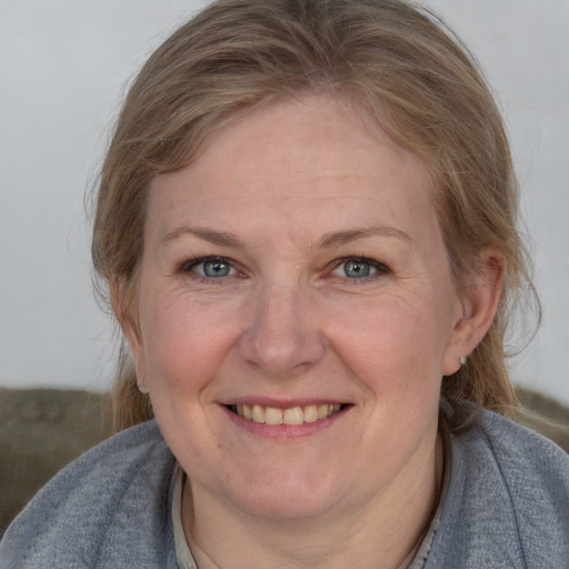 Joyful white adult female with medium  brown hair and blue eyes