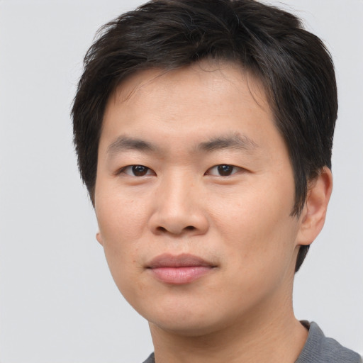 Joyful asian young-adult male with short  brown hair and brown eyes