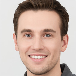 Joyful white young-adult male with short  brown hair and grey eyes