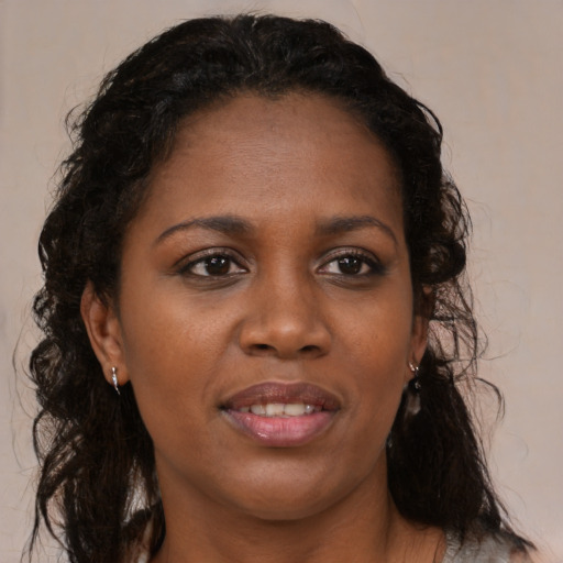 Joyful black young-adult female with long  brown hair and brown eyes