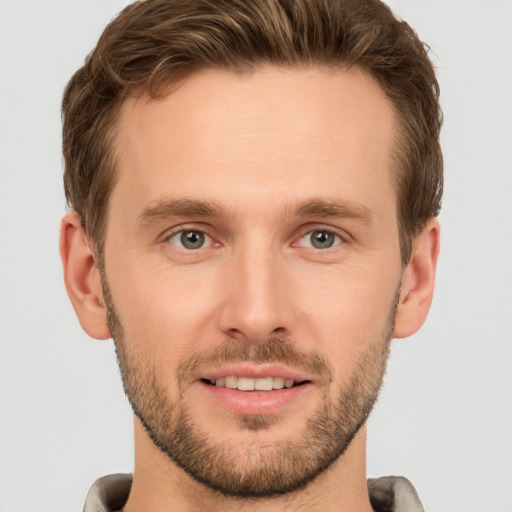 Joyful white young-adult male with short  brown hair and grey eyes