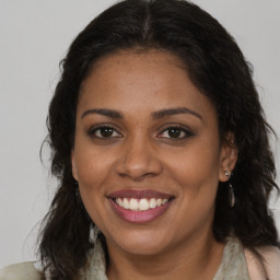 Joyful black young-adult female with long  brown hair and brown eyes