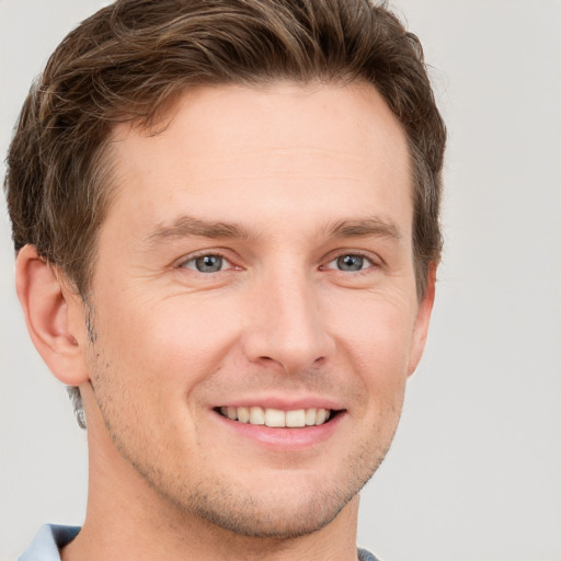 Joyful white young-adult male with short  brown hair and grey eyes