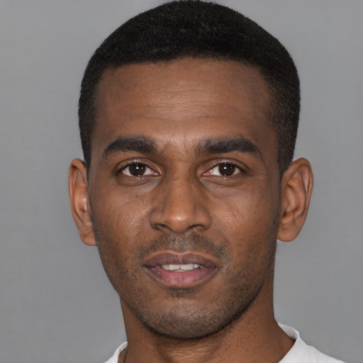 Joyful black young-adult male with short  black hair and brown eyes
