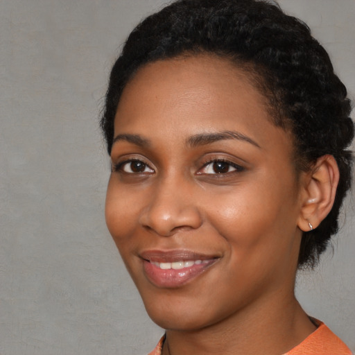 Joyful black young-adult female with short  black hair and brown eyes