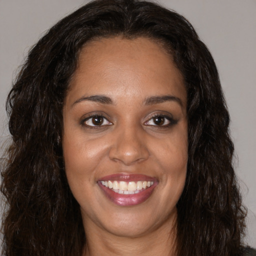 Joyful black young-adult female with long  brown hair and brown eyes
