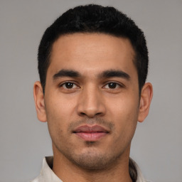 Joyful latino young-adult male with short  black hair and brown eyes