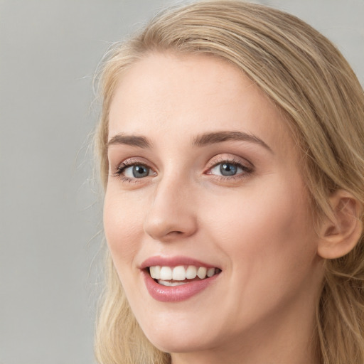 Joyful white young-adult female with long  brown hair and blue eyes