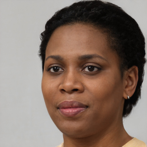 Joyful black young-adult female with short  black hair and brown eyes