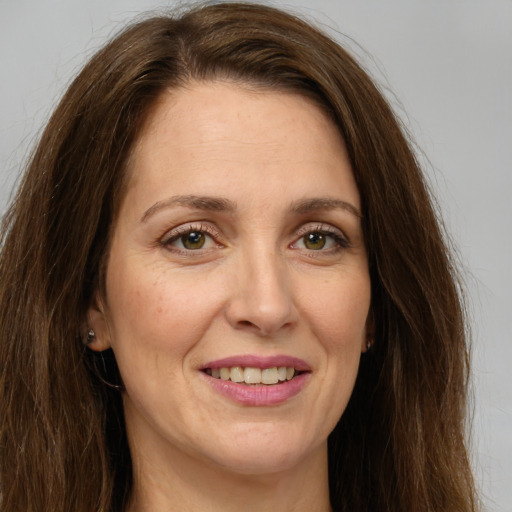 Joyful white adult female with long  brown hair and green eyes