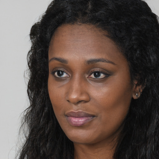 Joyful black young-adult female with long  black hair and brown eyes