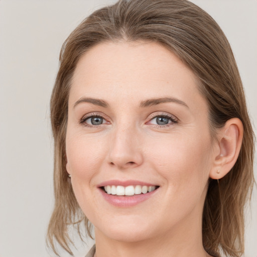 Joyful white young-adult female with medium  brown hair and grey eyes