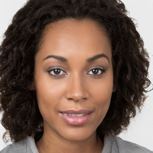 Joyful black young-adult female with long  brown hair and brown eyes