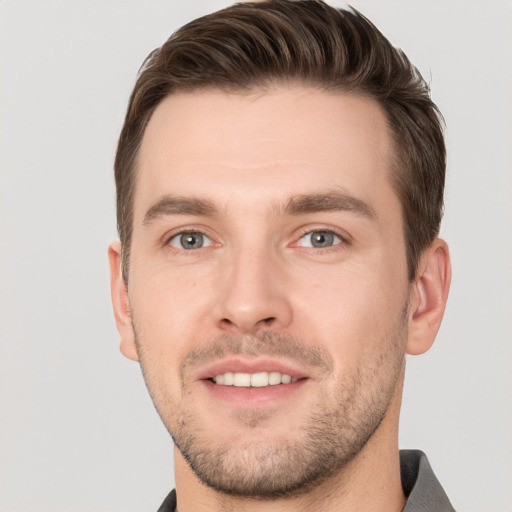 Joyful white young-adult male with short  brown hair and grey eyes