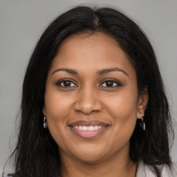 Joyful black adult female with long  brown hair and brown eyes