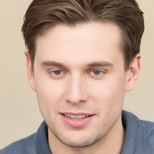 Joyful white young-adult male with short  brown hair and grey eyes