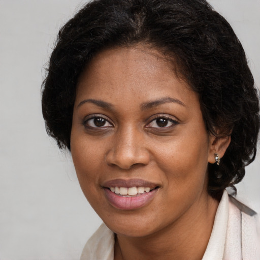 Joyful black young-adult female with long  brown hair and brown eyes