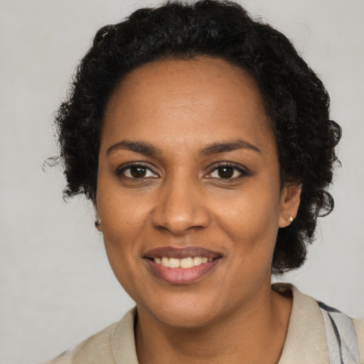 Joyful black young-adult female with long  brown hair and brown eyes