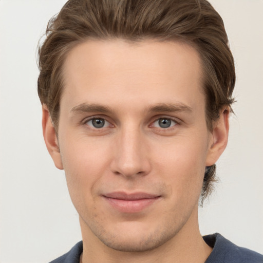 Joyful white young-adult male with short  brown hair and grey eyes