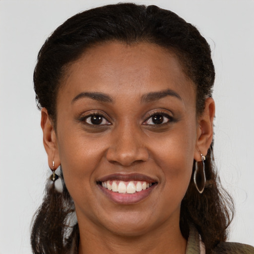 Joyful black young-adult female with long  brown hair and brown eyes