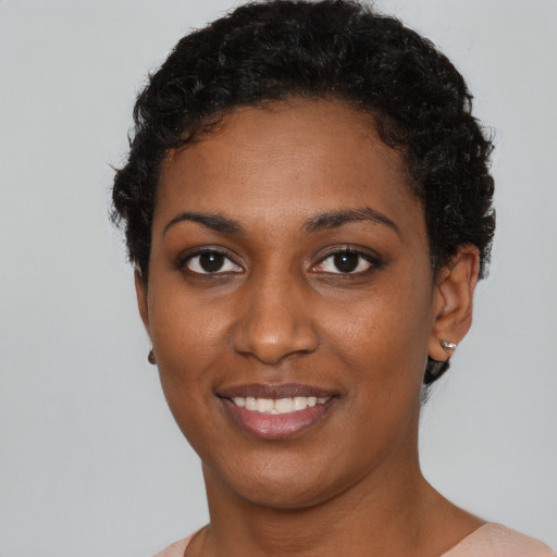 Joyful black young-adult female with short  black hair and brown eyes