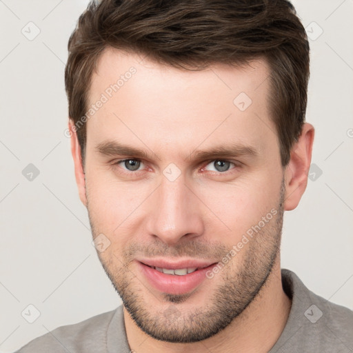 Joyful white young-adult male with short  brown hair and grey eyes