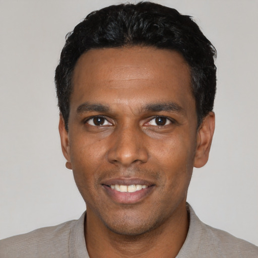Joyful black young-adult male with short  black hair and brown eyes