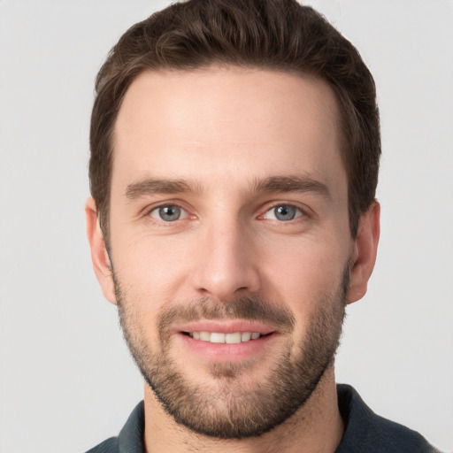 Joyful white young-adult male with short  brown hair and grey eyes